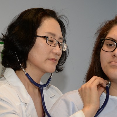 Asian NP nurse checking cartoid artery pulse of young hispanic women,